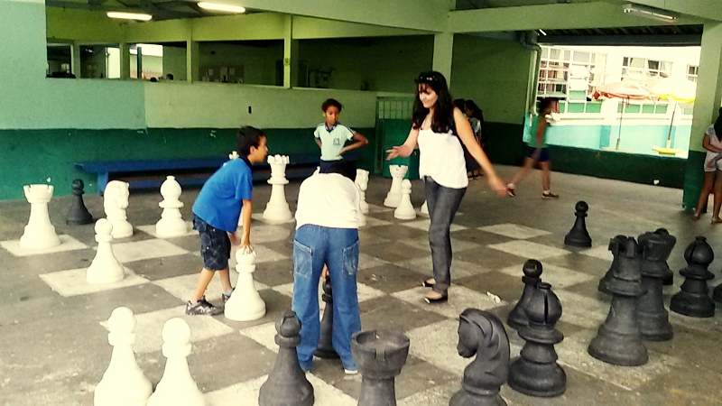Adriana ensinando em um tabuleiro de xadrez gigante