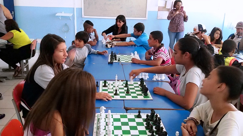 Alunos jogando xadrez sob orientação da Adriana