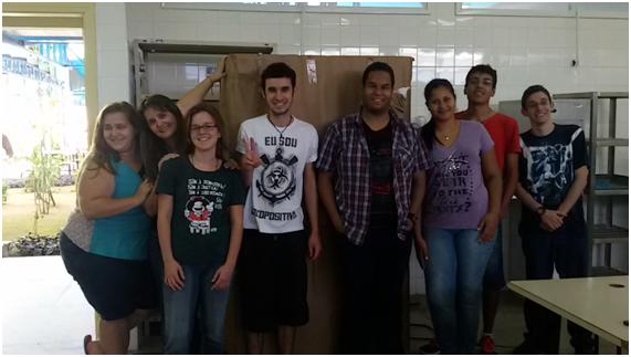 Estudantes junto ao armário do kit para o ensino de física ainda na embalagem