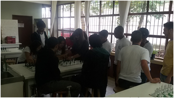 Adriana ensinando as regras do xadrez para um grupo de alunos