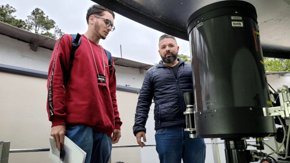 Imagem 10 – Gabriel ao lado de telescópio dentro do Miniobservatório Astronômico do INPE