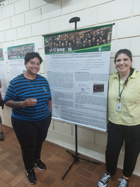  Imagem 3 – Nicoli ao lado do seu banner com a professora Ariane Braga Oliveira