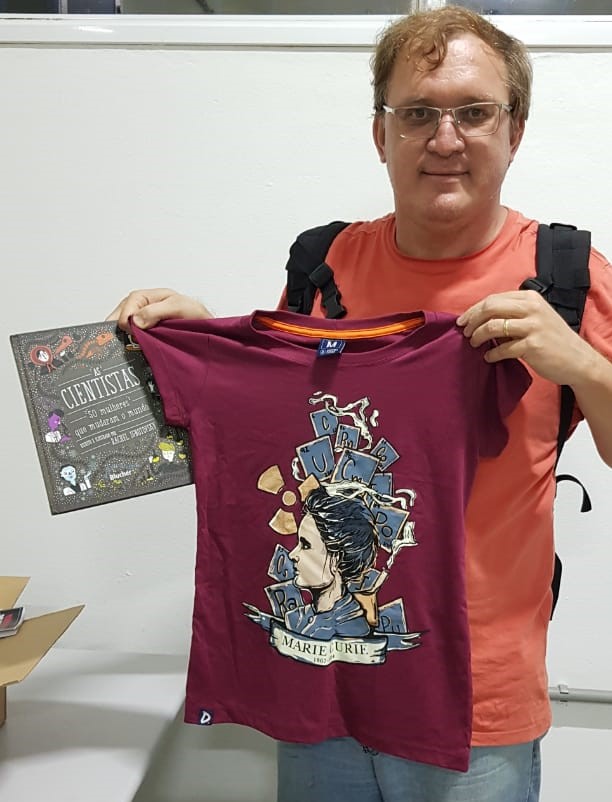 Professor Nelson com o livro e uma das camisetas que doou e que foram sorteados