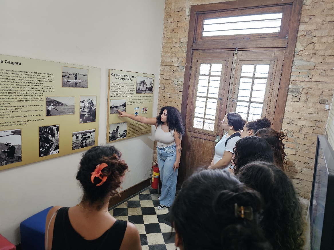 Imagem 6: No museu, a monitora Catarina mostra algumas fotos antigas da cidade e explica a histórica da construção da igreja matriz