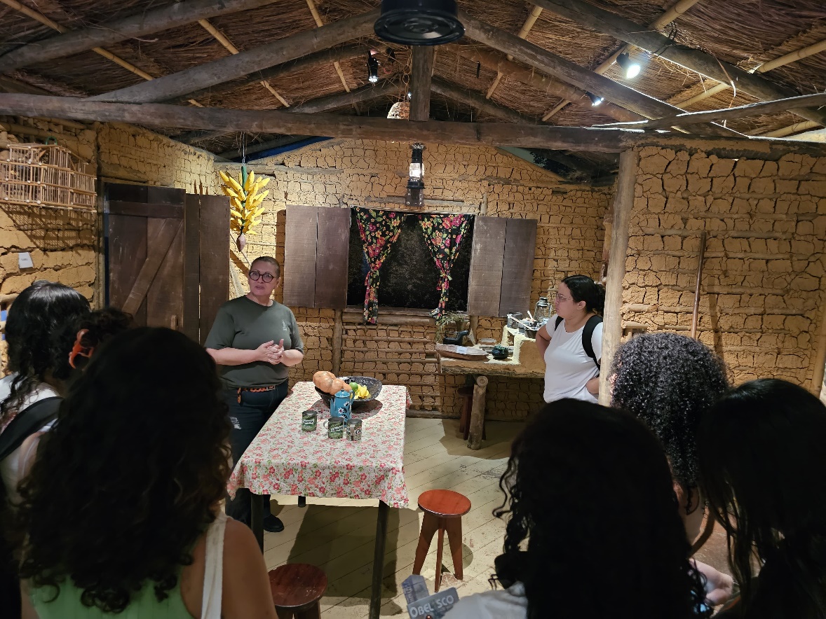 Imagem 7: Alunos com a monitora Marli na réplica de uma casa caiçara
