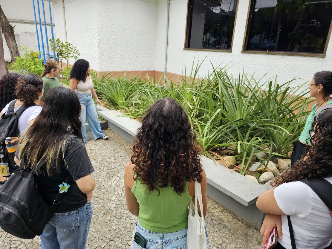 Imagem 9: Marli e Catarina mostram para os alunos a planta Caraguatá em frente ao museu
