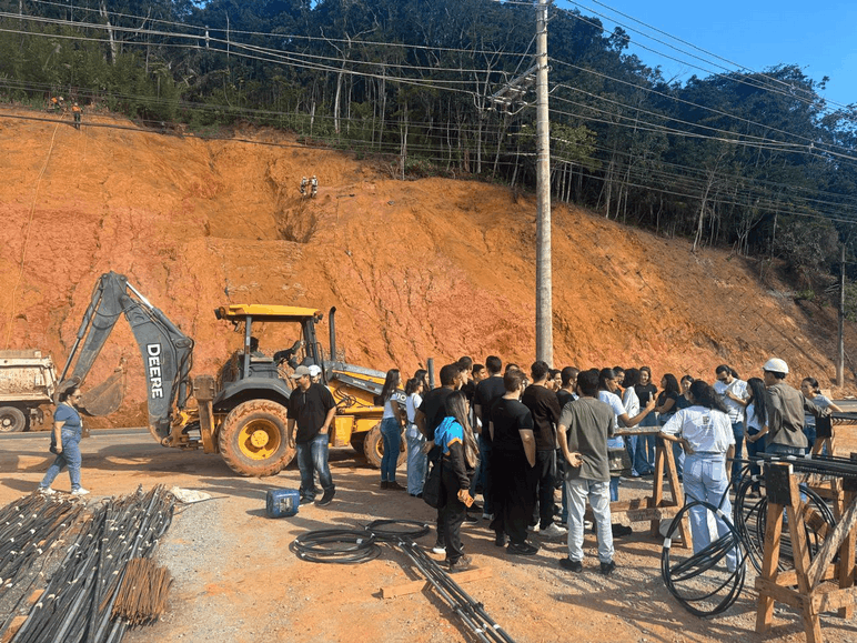 Foto 1: Canteiro de obra localizado na faixa non-aeadificandi da rodovia BR-101, destaque para trabalhadores suspensos por cordas para executar as obras no talude ao fundo.