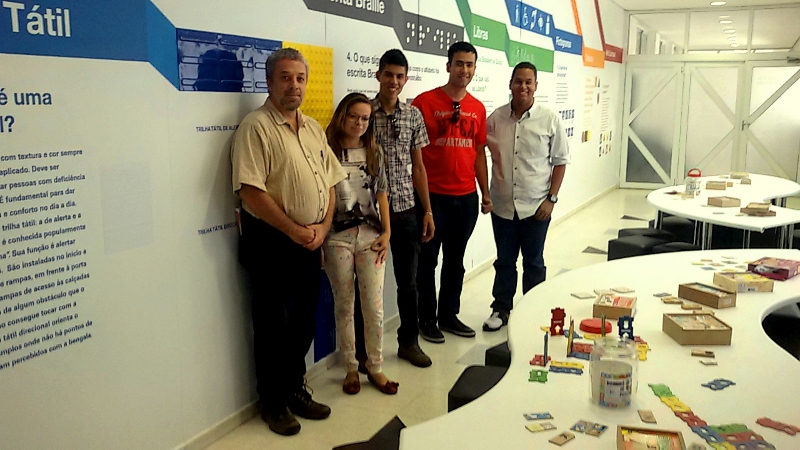     Professor Ricardo e estudantes junto a materiais didáticos de manipulação táctil.