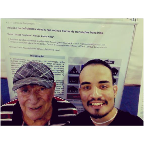 Antonio e Victor, à frente do pôster de autoria do último e do professor Nelson. 