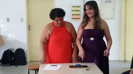 Cintia e Adriana apresentam um motor elétrico simples com fios, uma pilha e um imã