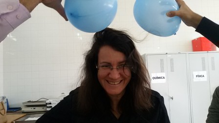 Marta eletrizando uma bexiga pelo atrito com seu cabelo
