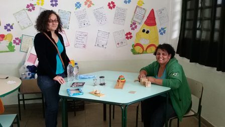Josiene e Cintia na mesa com jogos e desafios matemáticos