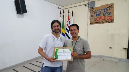 Professor Moacir recebendo do professor Cesar o certificado de apresentação da palestra