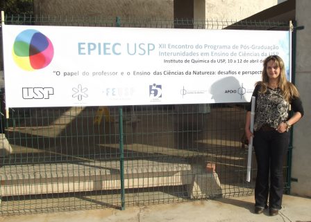 Adriana em frente a uma faixa informando sobre o XII EPIEC